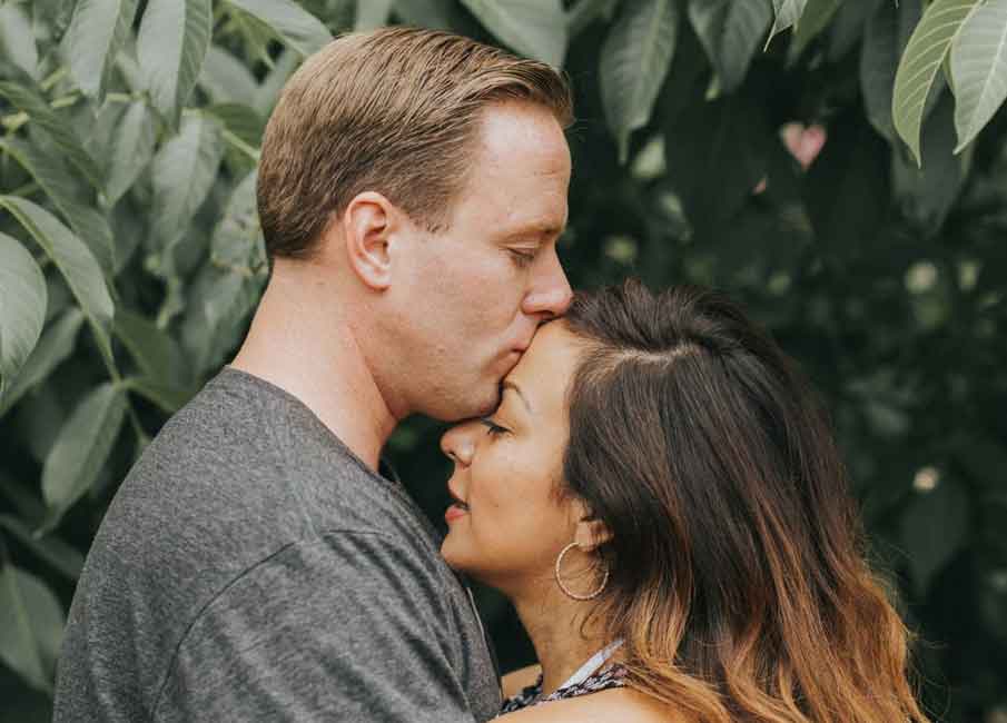 man kissing his wife’s forehead